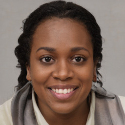 Joyful black young-adult female with long  brown hair and brown eyes