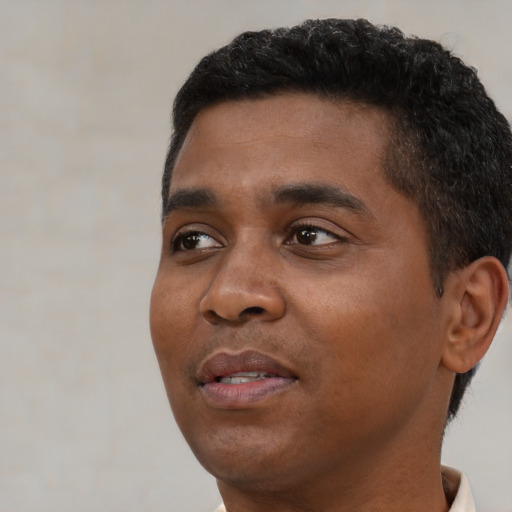Joyful black young-adult male with short  black hair and brown eyes