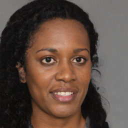 Joyful black young-adult female with long  brown hair and brown eyes