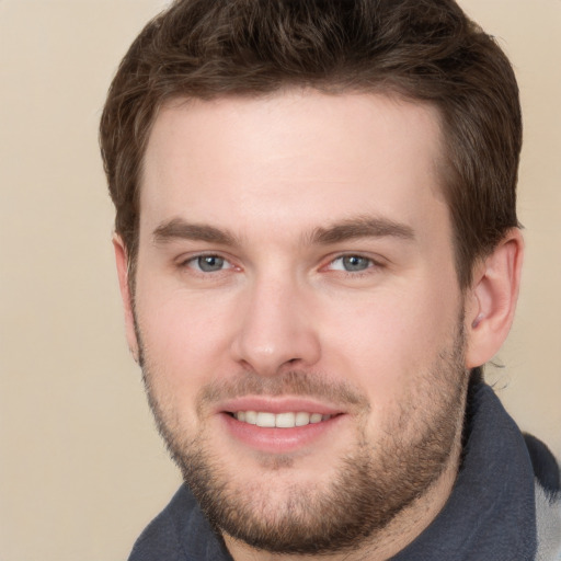 Joyful white young-adult male with short  brown hair and grey eyes