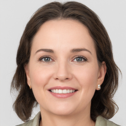 Joyful white young-adult female with medium  brown hair and grey eyes