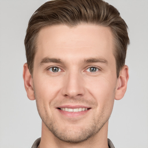 Joyful white young-adult male with short  brown hair and grey eyes