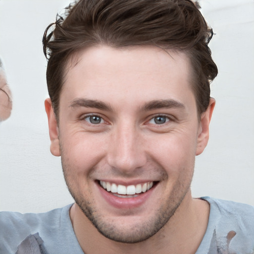 Joyful white young-adult male with short  brown hair and grey eyes