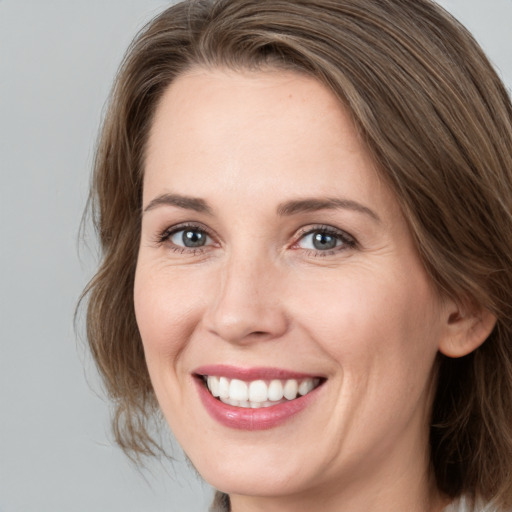 Joyful white young-adult female with medium  brown hair and grey eyes