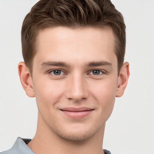 Joyful white young-adult male with short  brown hair and grey eyes