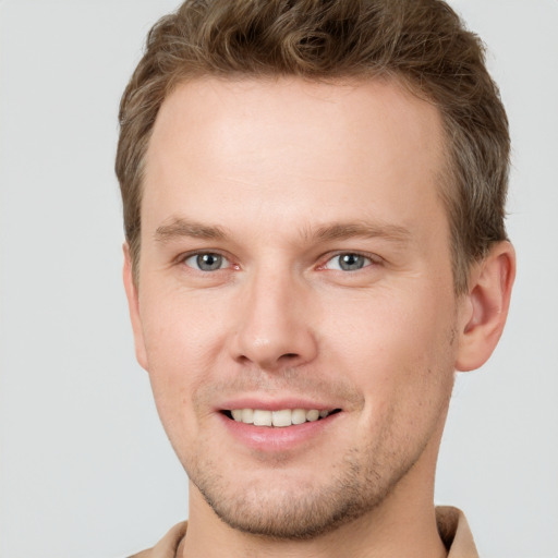 Joyful white young-adult male with short  brown hair and grey eyes