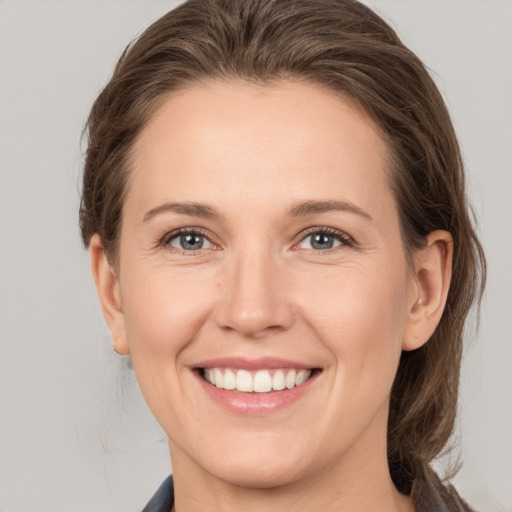 Joyful white young-adult female with medium  brown hair and grey eyes