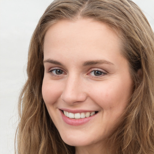 Joyful white young-adult female with long  brown hair and blue eyes