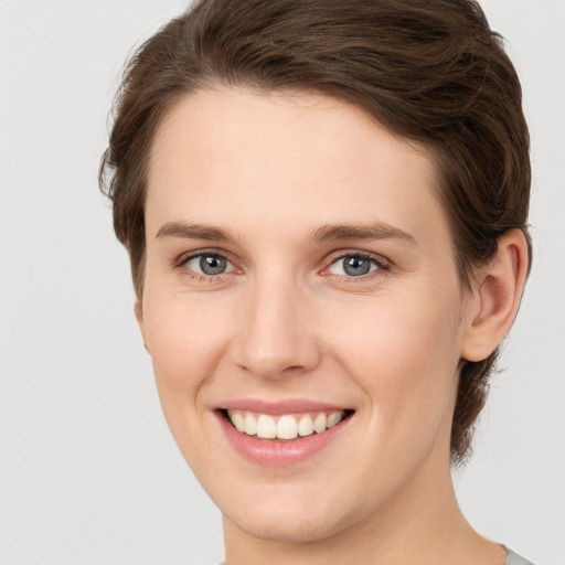 Joyful white young-adult female with short  brown hair and grey eyes