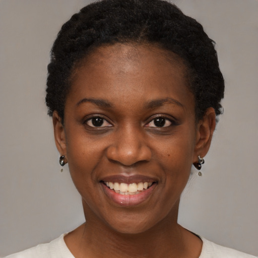 Joyful black young-adult female with short  black hair and brown eyes