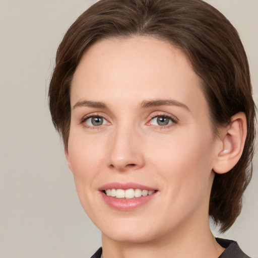 Joyful white young-adult female with medium  brown hair and grey eyes