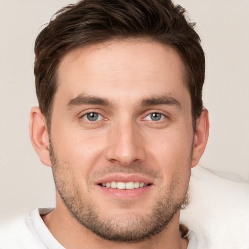 Joyful white young-adult male with short  brown hair and grey eyes