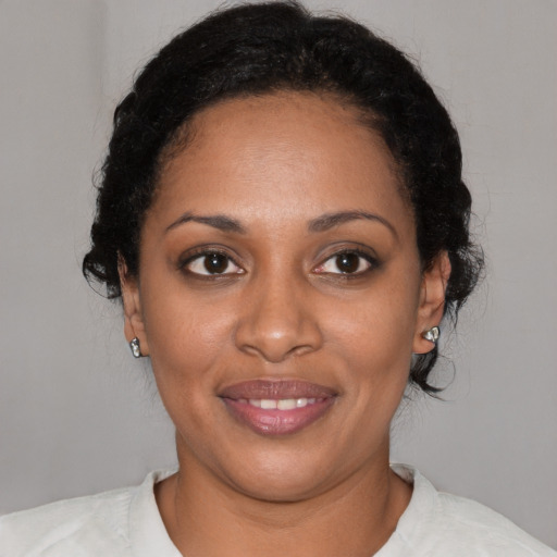 Joyful black young-adult female with short  black hair and brown eyes