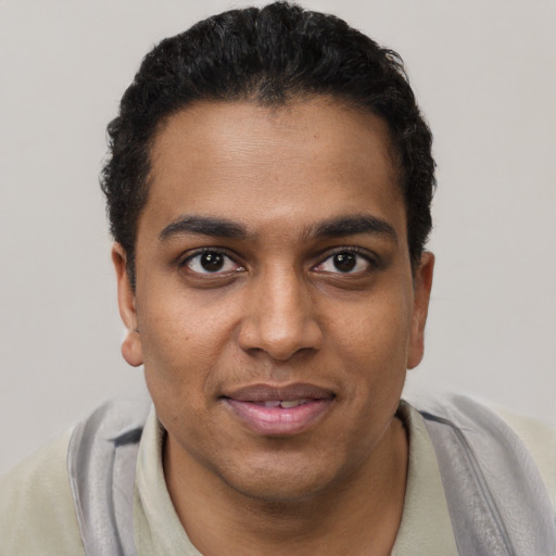 Joyful black young-adult male with short  brown hair and brown eyes