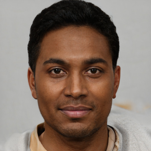 Joyful black young-adult male with short  black hair and brown eyes