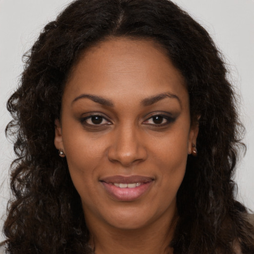 Joyful black young-adult female with long  brown hair and brown eyes