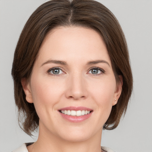 Joyful white young-adult female with medium  brown hair and grey eyes