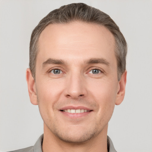 Joyful white young-adult male with short  brown hair and grey eyes