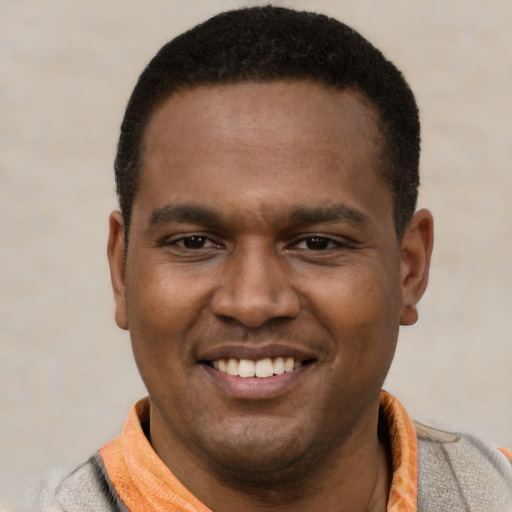 Joyful black young-adult male with short  black hair and brown eyes