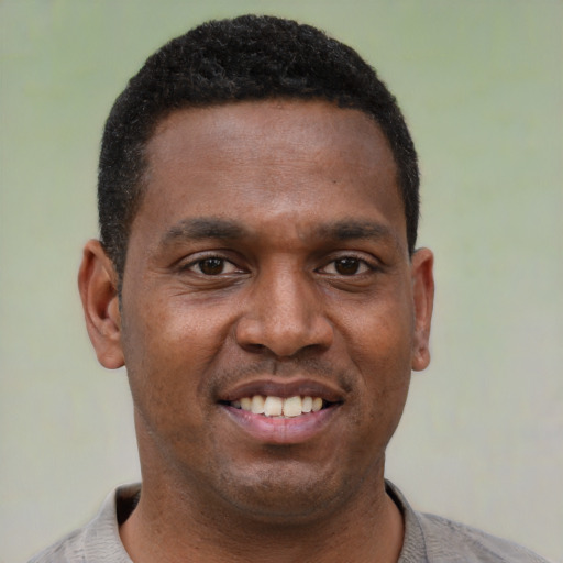 Joyful black young-adult male with short  black hair and brown eyes
