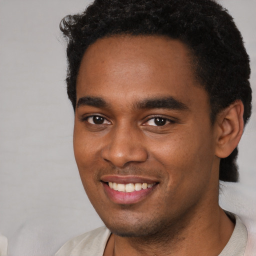 Joyful black young-adult male with short  black hair and brown eyes