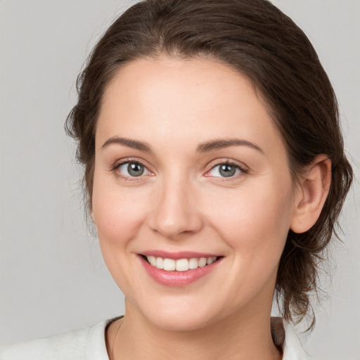 Joyful white young-adult female with medium  brown hair and grey eyes