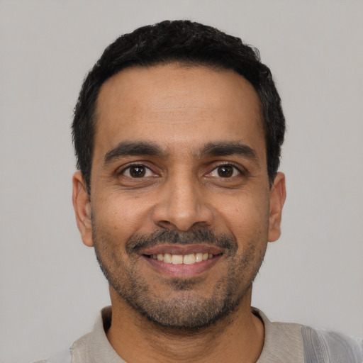 Joyful latino young-adult male with short  black hair and brown eyes