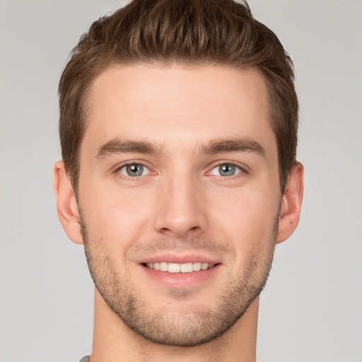 Joyful white young-adult male with short  brown hair and grey eyes