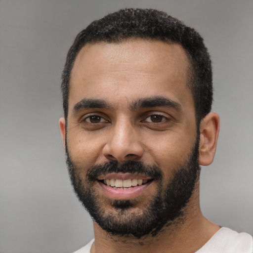 Joyful black young-adult male with short  black hair and brown eyes