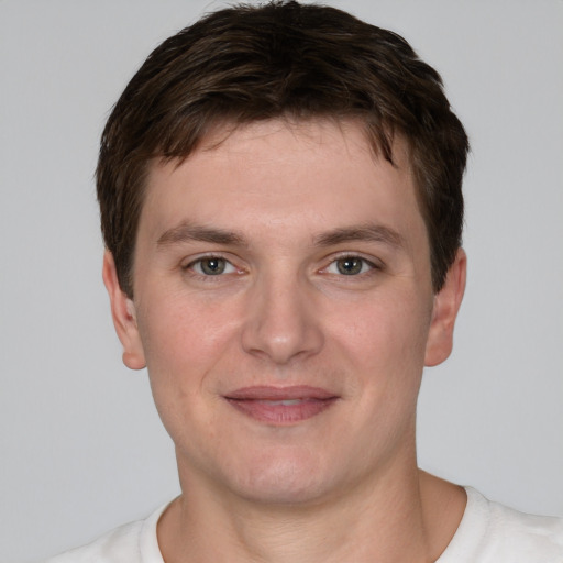 Joyful white young-adult male with short  brown hair and grey eyes