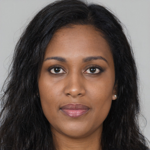 Joyful black young-adult female with long  brown hair and brown eyes