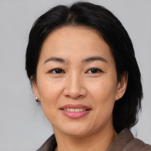 Joyful asian adult female with medium  brown hair and brown eyes