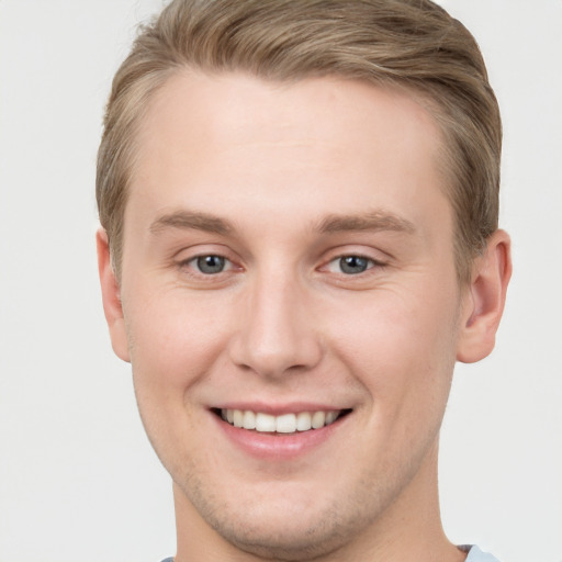 Joyful white young-adult male with short  brown hair and grey eyes