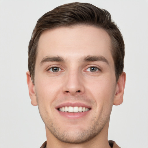 Joyful white young-adult male with short  brown hair and grey eyes