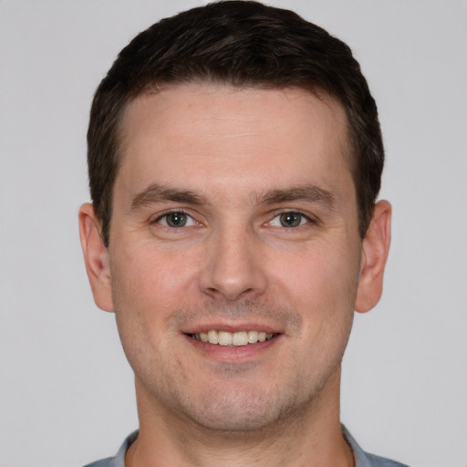 Joyful white young-adult male with short  brown hair and grey eyes