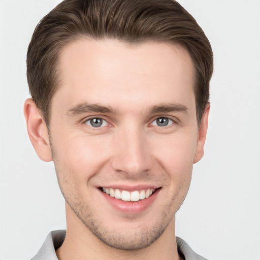 Joyful white young-adult male with short  brown hair and grey eyes