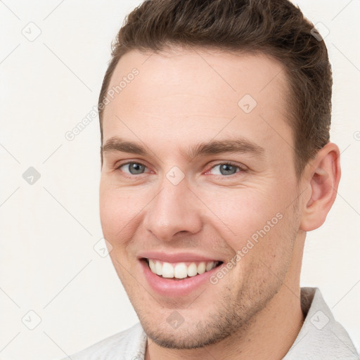 Joyful white young-adult male with short  brown hair and grey eyes