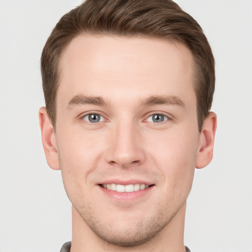 Joyful white young-adult male with short  brown hair and grey eyes