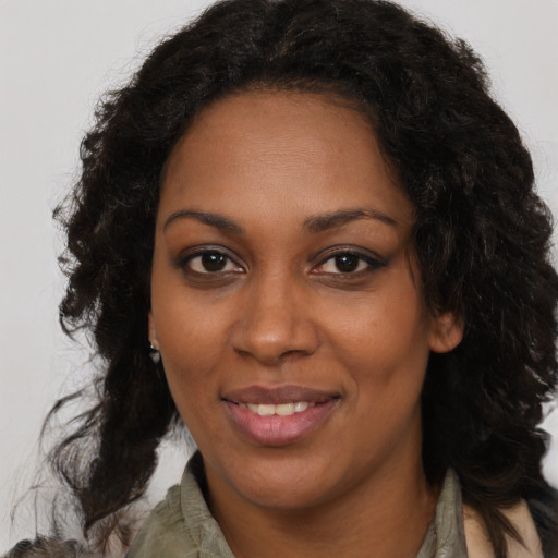 Joyful black young-adult female with long  brown hair and brown eyes