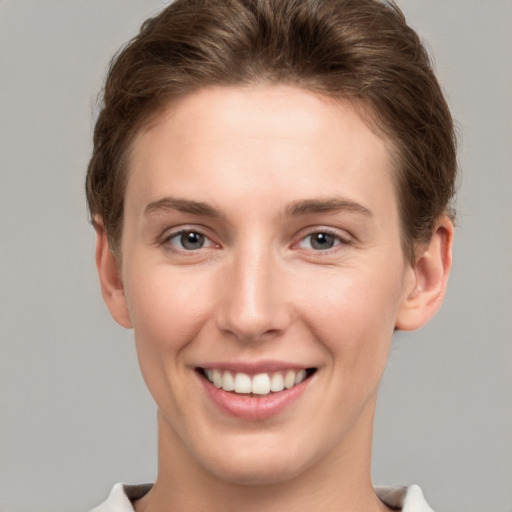 Joyful white young-adult female with short  brown hair and grey eyes