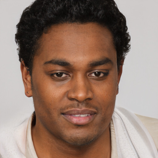 Joyful black young-adult male with short  brown hair and brown eyes