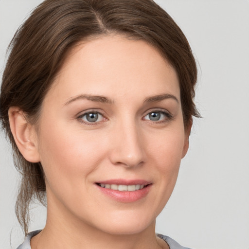 Joyful white young-adult female with medium  brown hair and grey eyes