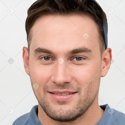 Joyful white young-adult male with short  brown hair and grey eyes