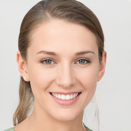 Joyful white young-adult female with medium  brown hair and grey eyes