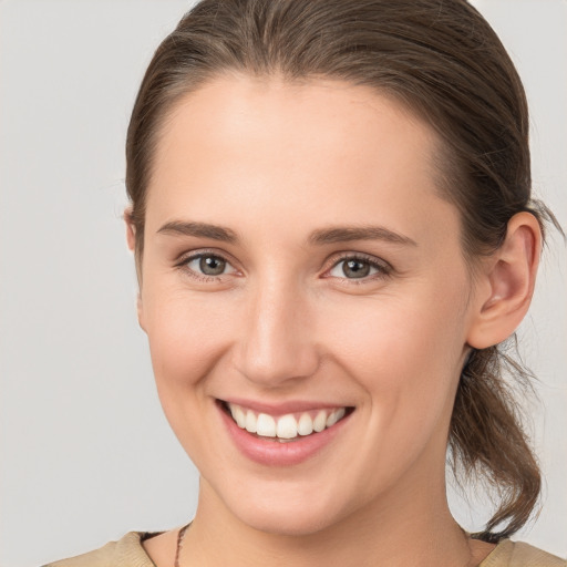 Joyful white young-adult female with medium  brown hair and grey eyes