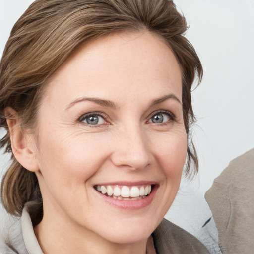 Joyful white young-adult female with medium  brown hair and grey eyes