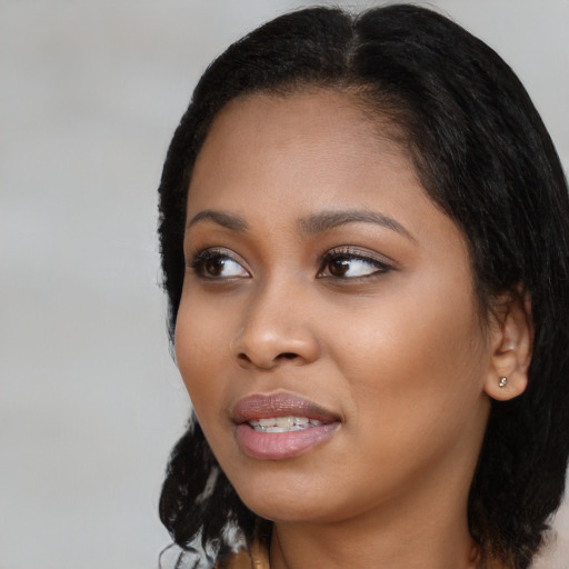 Joyful black young-adult female with long  black hair and brown eyes
