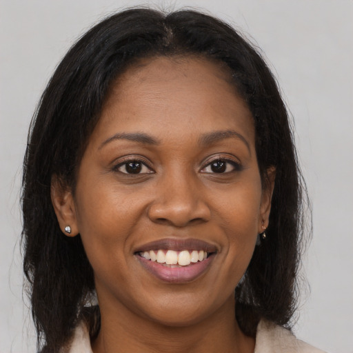 Joyful black young-adult female with long  brown hair and brown eyes