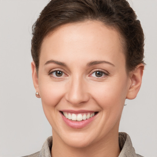 Joyful white young-adult female with short  brown hair and grey eyes