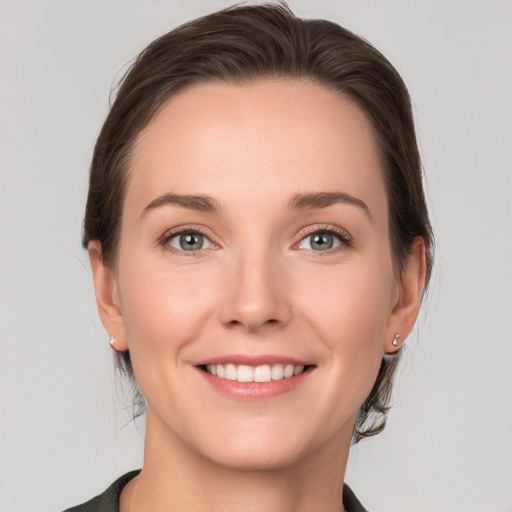 Joyful white young-adult female with medium  brown hair and grey eyes